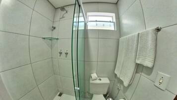 Un baño compacto con cabina de ducha de vidrio, un inodoro y un ventanal que proporciona luz natural.