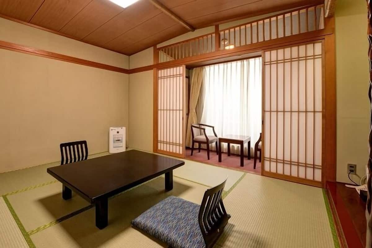 A traditional Japanese room with tatami flooring, a low table, chairs, and shoji screens.