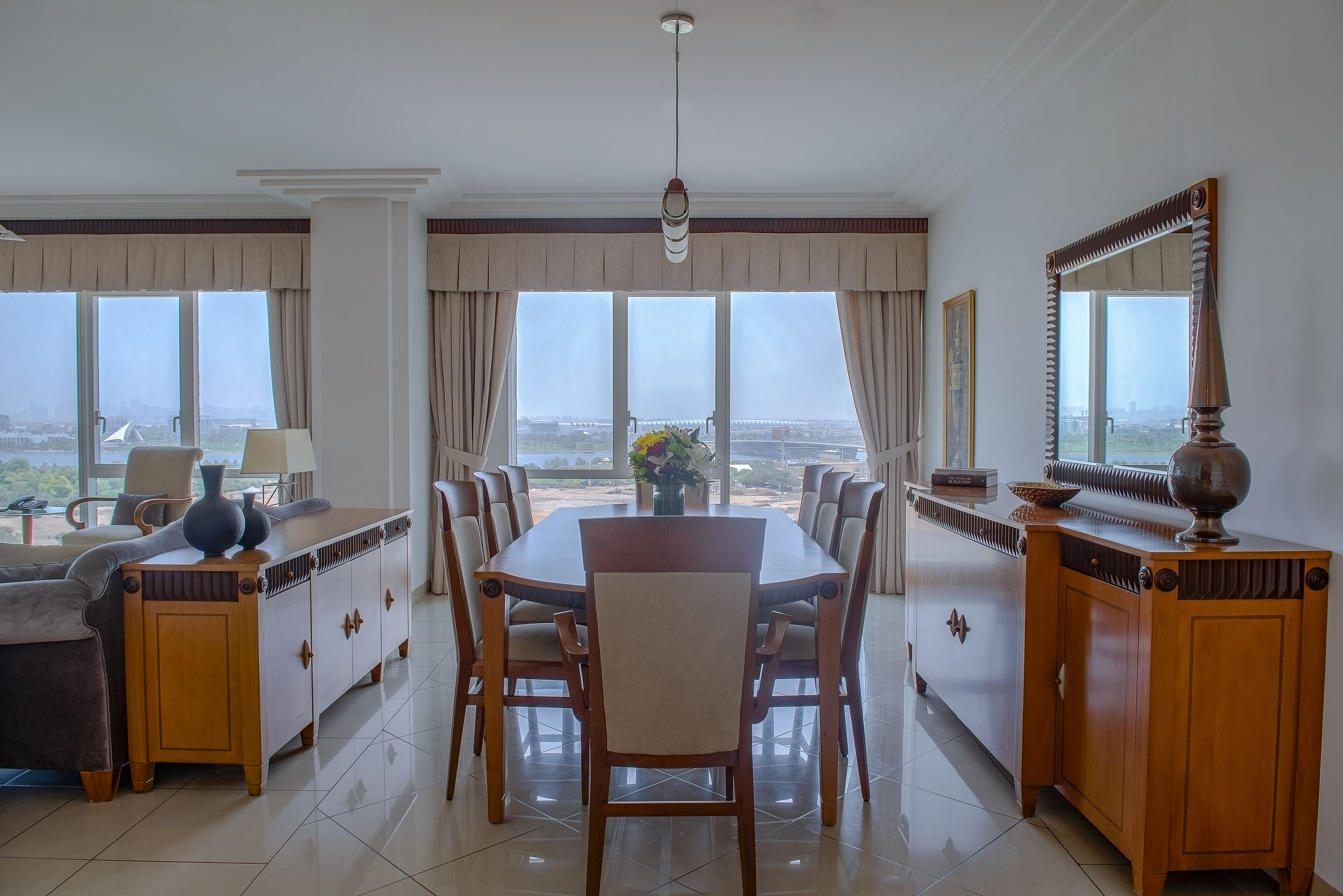 A dining area with a large wooden table, multiple chairs, a sofa, and a cabinet.