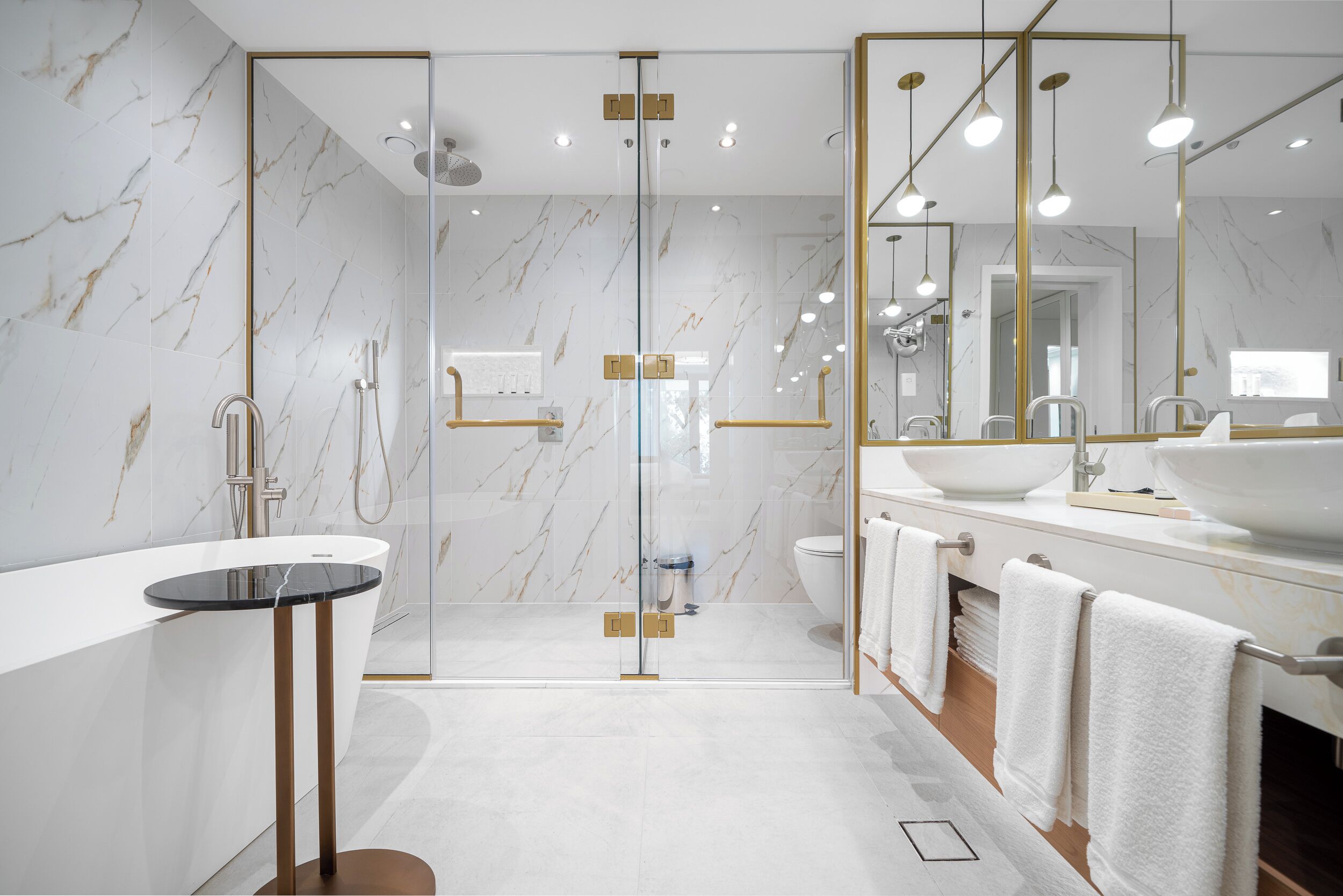 A modern bathroom with a glass-enclosed shower, a freestanding bathtub, and a large mirror with gold accents.