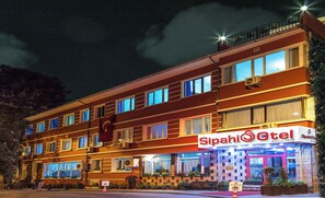 A multi-story hotel with a prominent "Sipahi Hotel" sign, featuring a traditional design with large windows and a balcony on the upper floor.