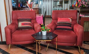 Two red armchairs with striped cushions, a small black table with a white vase, and a potted plant. - Sipahi (Istanbul)
