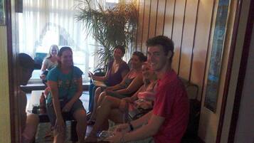 A group of people seated in a room with wooden walls and a large plant.