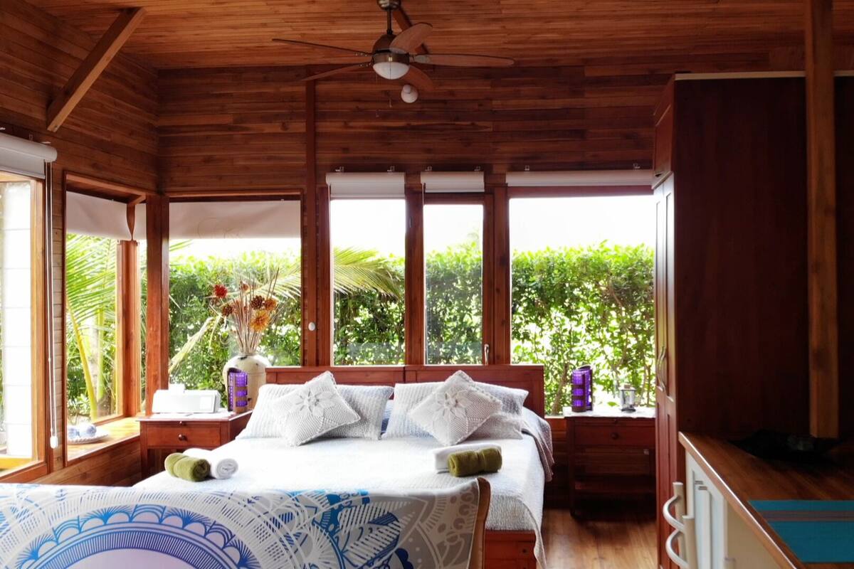 Une chambre dans un chalet en bois, avec un lit, un bureau et une fenêtre donnant sur un paysage verdoyant.