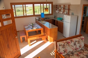 A compact kitchen with wooden cabinets, a built-in island, and a refrigerator. - Chez Manany Galapagos Eco lodge (Puerto Villamil)