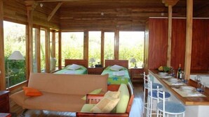 Una cabaña de madera con dos camas, un sofá, una mesa de comedor y taburetes de bar.