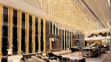 A spacious lobby with a modern chandelier, seating area, and a bar.