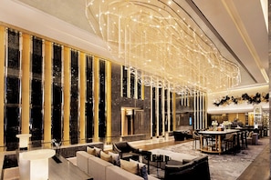 Un hall d’entrée spacieux agrémenté d’un lustre moderne, d’un coin salon et d’un bar.