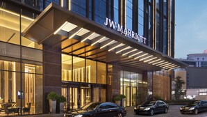 A JW Marriott hotel with a modern glass facade, a covered entrance, and multiple cars parked in front. - JW Marriott Hotel Chengdu (Chengdu)