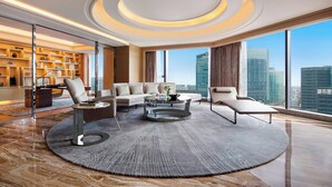 A modern living room with a circular rug, a sofa, two armchairs, and a coffee table. A bookshelf is visible in the background. - JW Marriott Hotel Chengdu (Chengdu)