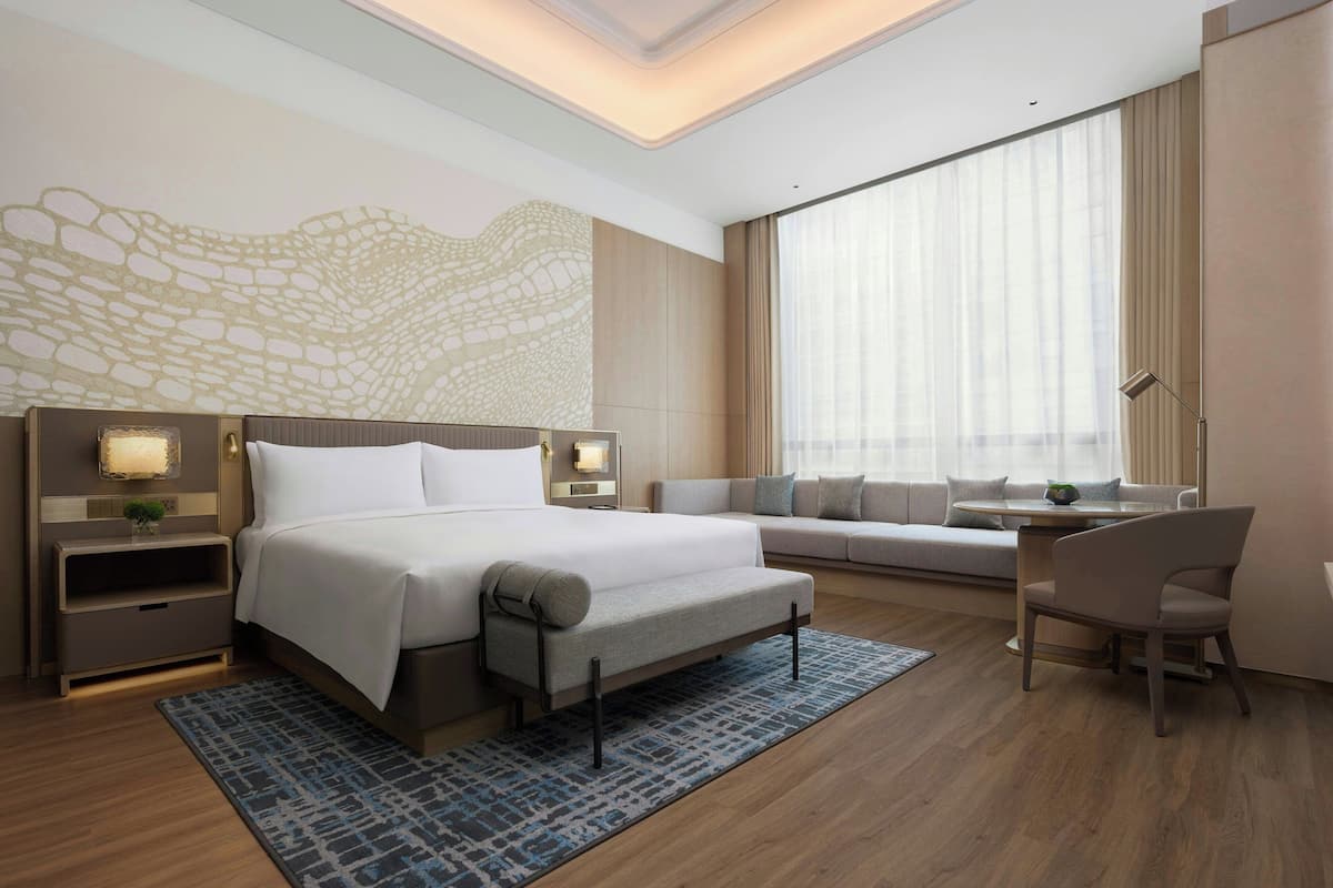 Una habitación de hotel moderna con una cama grande, un sofá, un escritorio y una silla.
