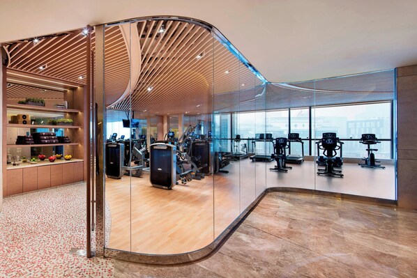 A modern gym with exercise equipment, a wooden ceiling, and a large window offering a city view. - JW Marriott Hotel Chengdu (Chengdu)