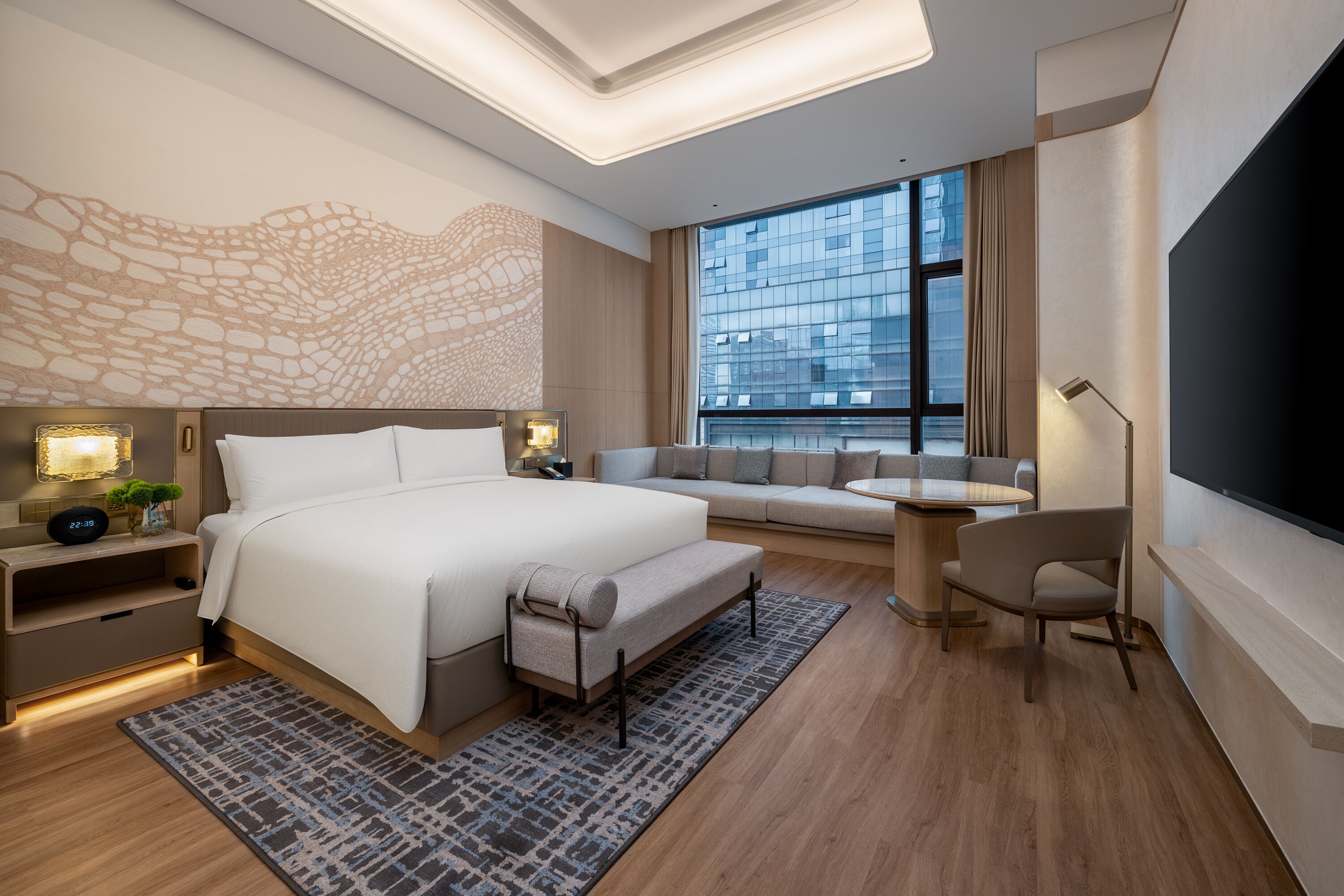 Une chambre d’hôtel moderne équipée d’un grand lit, d’un canapé, d’un bureau et d’une télévision.