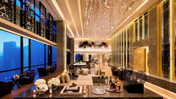 A luxurious hotel lobby with a high ceiling, a chandelier, a seating area with sofas and chairs, a dining table, and a large window offering a city view. - JW Marriott Hotel Chengdu (Chengdu)