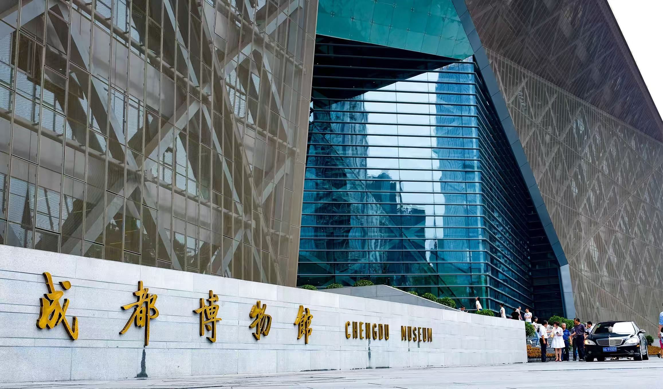 A modern building with a reflective glass facade and a prominent entrance with golden lettering.