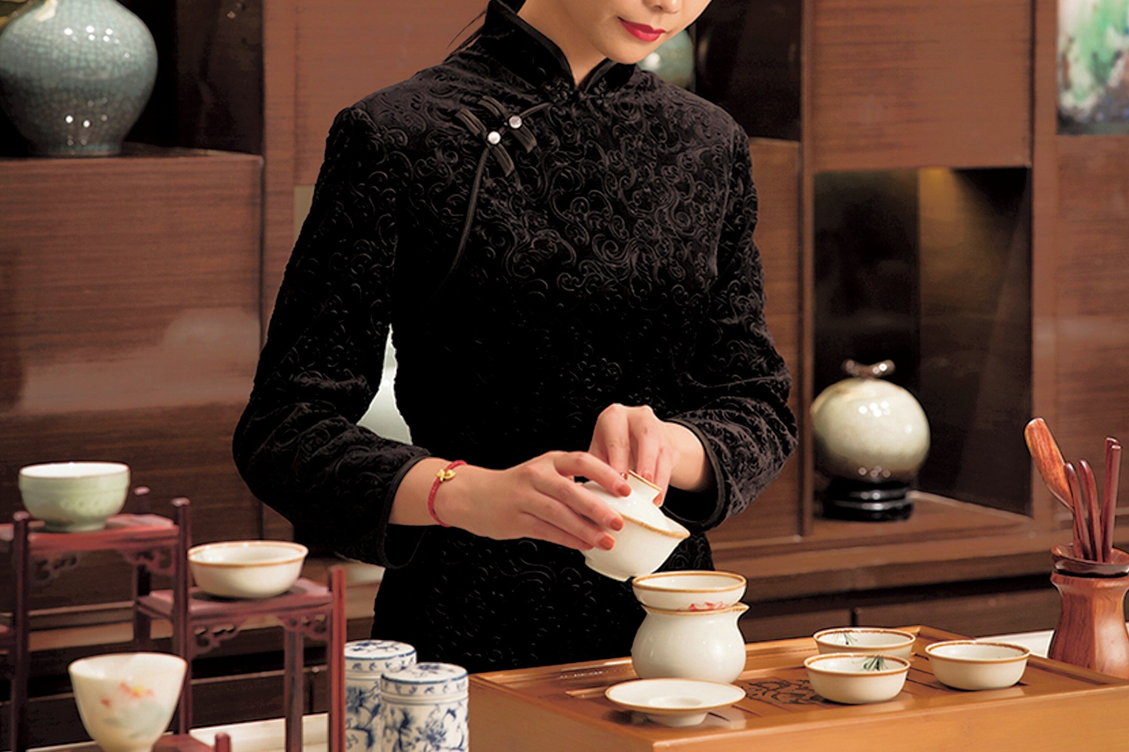 A person in traditional attire pouring tea into a cup.