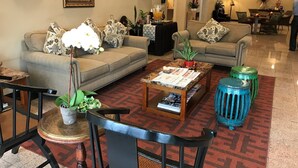 Ein Wohnzimmer mit zwei Sofas, einem Couchtisch, einem kleinen Tisch mit Pflanze und einem gemusterten Teppich.