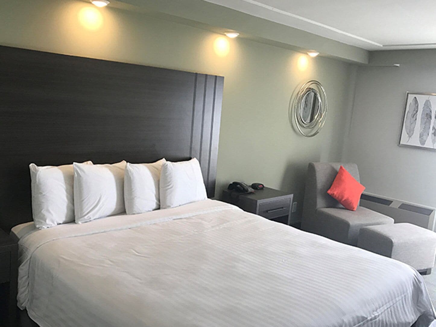 A hotel room with a large bed, a desk, a chair, and a wall-mounted phone.