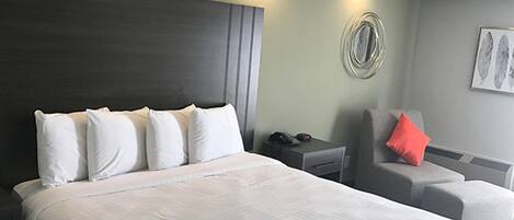 A hotel room with a large bed, a desk, a chair, and a wall-mounted phone.