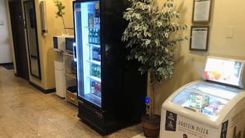 Un hall d’hôtel équipé d’un distributeur automatique de boissons en libre-service, d’un présentoir réfrigéré et d’un distributeur automatique de pizzas riches en protéines.