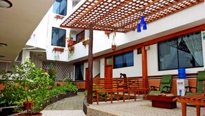 A multi-level outdoor area with wooden benches, potted plants, and a covered seating area. - Hotel Brisas Del Pacifico (Puerto Ayora)