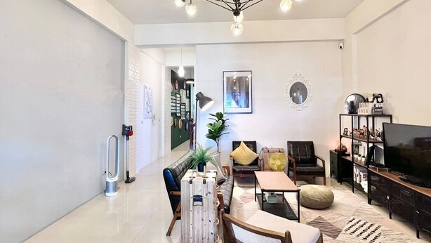 A modern living room with a high ceiling, a central chandelier, a television, and a seating area with a coffee table and chairs. - Three Brothers B&B (Taitung)