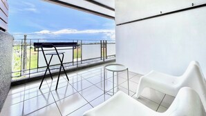 A balcony with a view of the sea, a small table, and two white chairs. - Three Brothers B&B (Taitung)