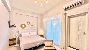 A bedroom with a bed, bedside table, fan, and a chair. - Three Brothers B&B (Taitung)