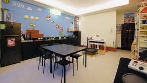 A compact kitchen with a dining area, featuring a refrigerator, stove, and a wall with Mario-themed decorations. - Huadong Homestay (Taitung)