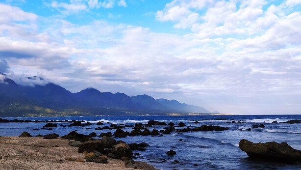 A coastal landscape with rocky terrain and mountains in the background. - Huadong Homestay (Taitung)