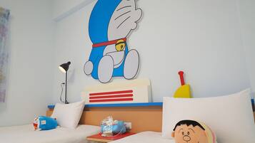 A hotel room with two beds, a large wall mural of a cartoon character, a lamp, a stuffed toy, and a pillow.