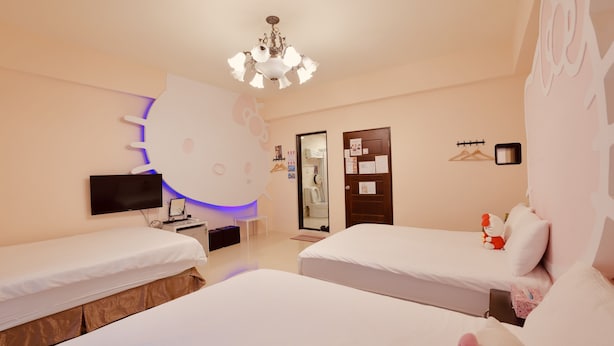 A hotel room with two beds, a flat-screen TV, a wall-mounted light fixture, and a door with a mirror and a coat rack.