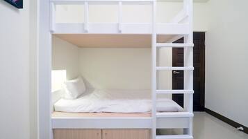 Una cama litera con una escalera, una mesita de noche y una puerta al fondo.