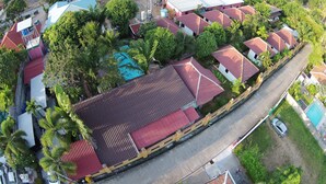 An aerial view of a residential area with multiple houses, a swimming pool, and a road. - Bee Nat Garden Resort (Koh Samui)