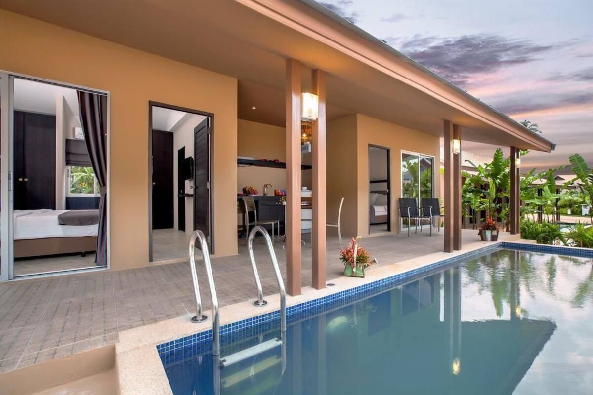 A modern hotel room with a pool, a balcony, and a view of the surrounding landscape.