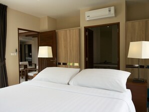 Hotelkamer met een bed, twee bedlampen, een airconditioning, een bureau met stoel en een spiegel.