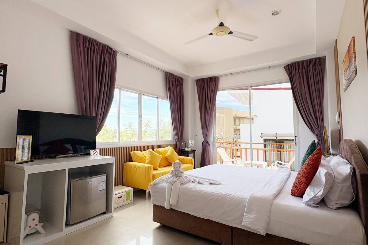 Une chambre d’hôtel moderne équipée d’un lit, d’une télévision, d’un bureau et d’un balcon.