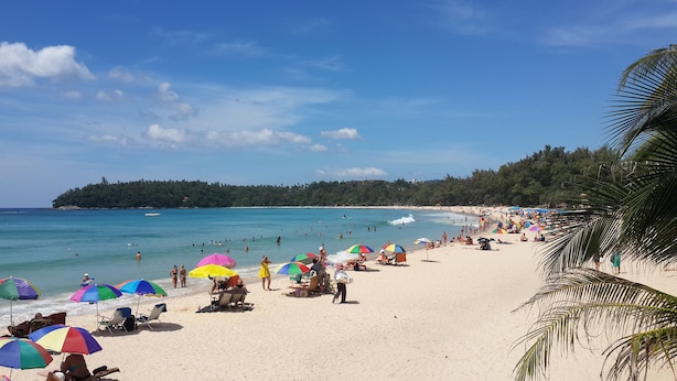 Una playa con gente, sombrillas y un cielo despejado.