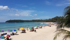 A beach with people, umbrellas, and a clear sky. - Kata Beachwalk Hotel and Bungalows (Karon)
