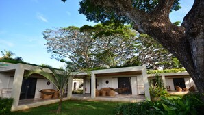 Un resort moderno con varias habitaciones, una hamaca y abundante vegetación.