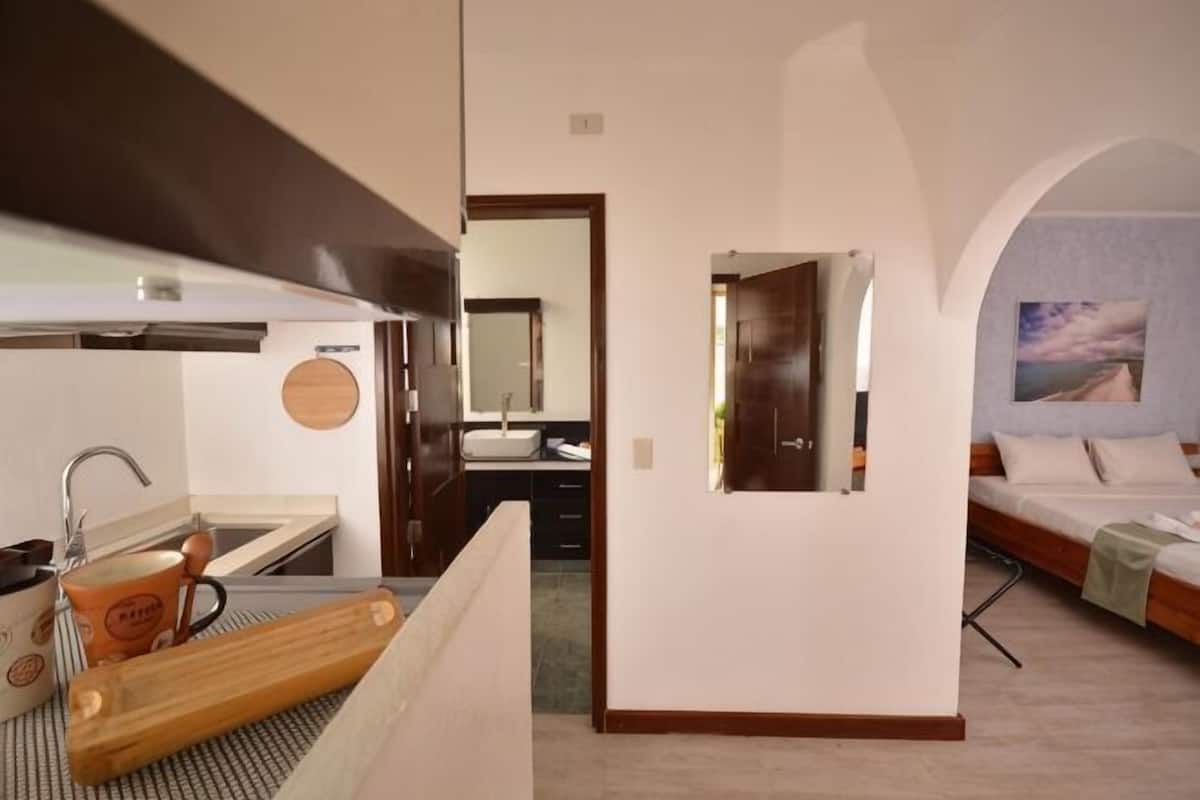 Habitación de hotel con kitchenette, una cama, baño con espejo y vistas al exterior.