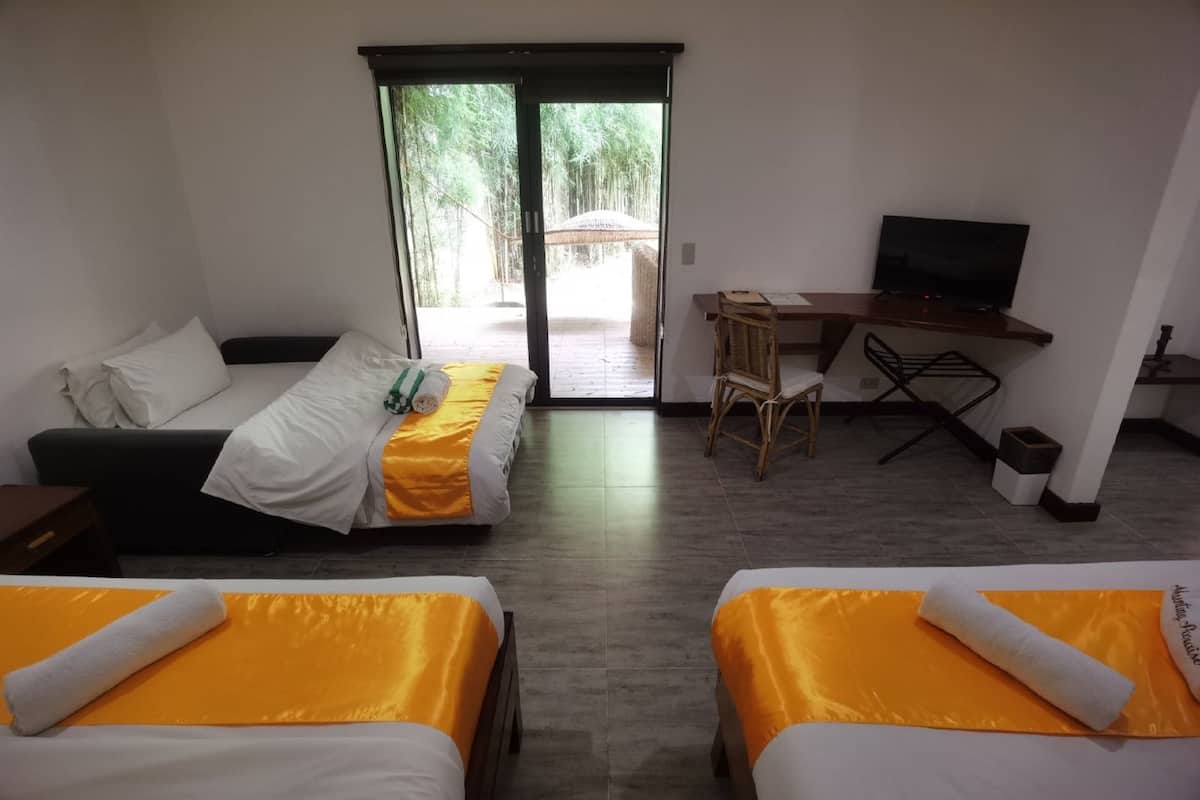 Habitación de hotel con dos camas, un escritorio, una silla y un televisor.