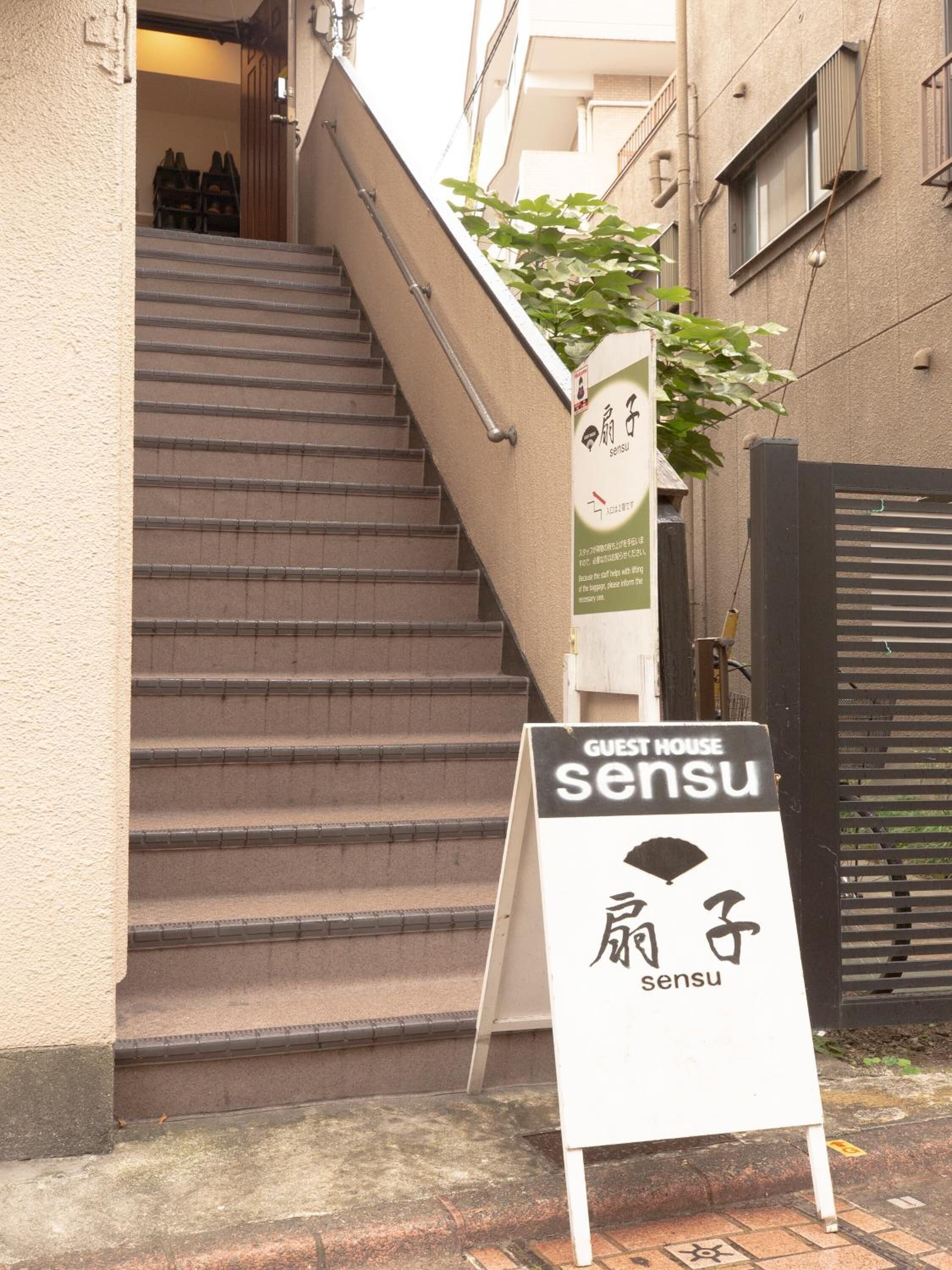 A staircase leading to a building with a signboard for 'Guest House sensu'.