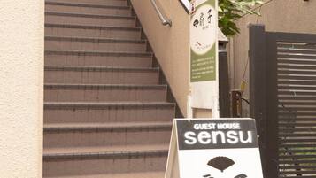 A staircase leading to a building with a signboard for 'Guest House sensu'.