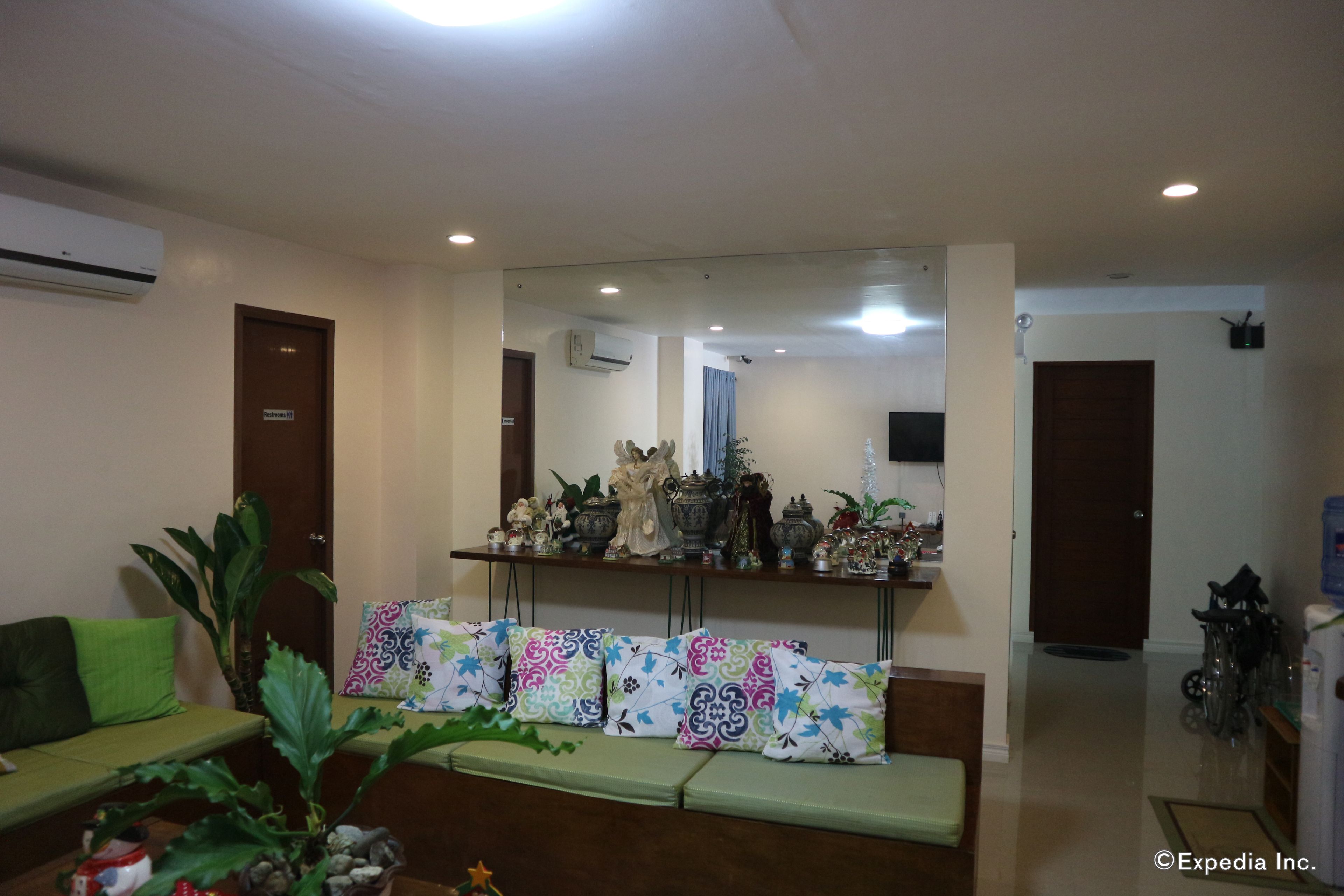 A reception area with a sofa, a bench, a mirror, and a shelf with decorative items.