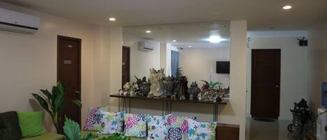 A reception area with a sofa, a bench, a mirror, and a shelf with decorative items.