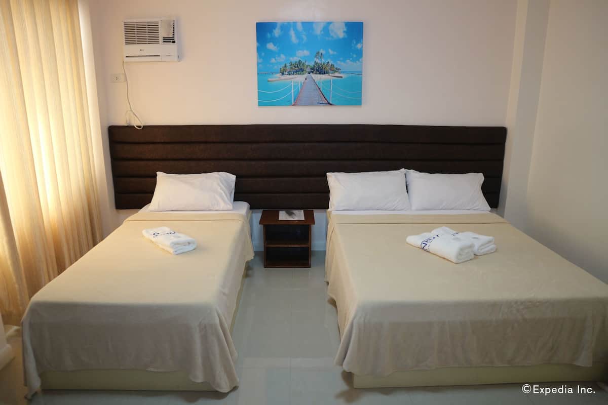 A hotel room with two single beds, a wooden headboard, a painting of a tropical island, and an air conditioning unit on the wall.