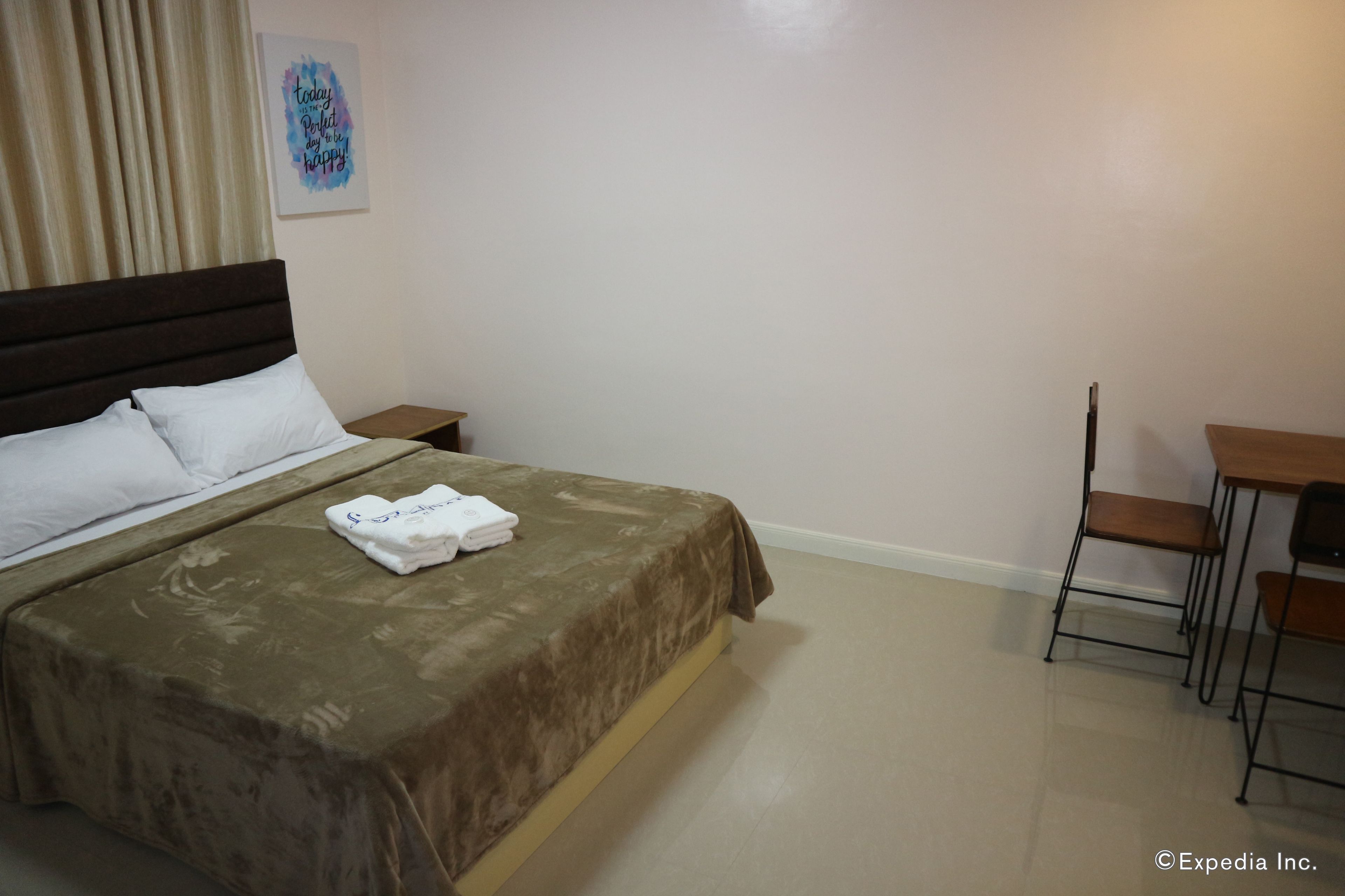 A hotel room with a bed, a nightstand, a desk, and a chair.
