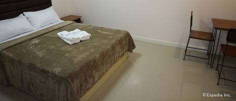 A hotel room with a bed, a nightstand, a desk, and a chair.