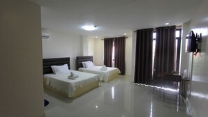 Une chambre d’hôtel avec deux lits, un bureau, une chaise, une télévision et un appareil de climatisation.